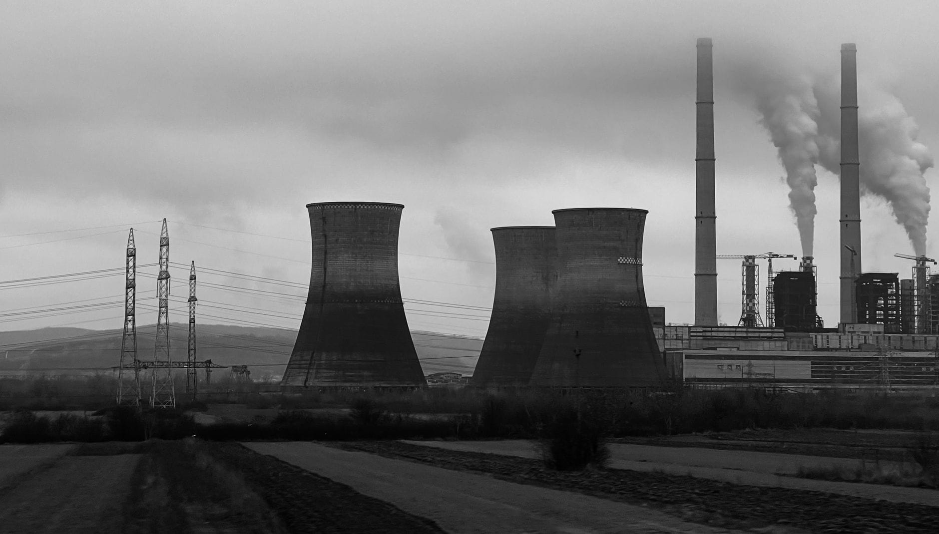 Elektrownia z chłodniami kominowymi i kominami na tle dymu