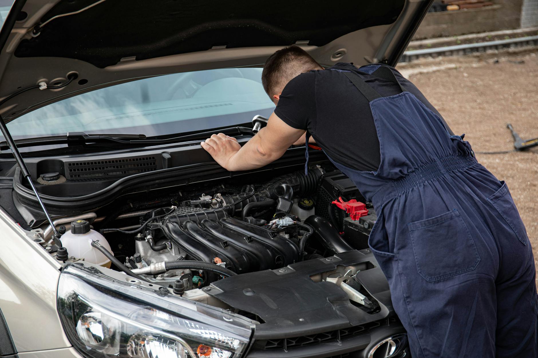 Mechanik sprawdzający silnik samochodu na zewnątrz podczas przeglądu
