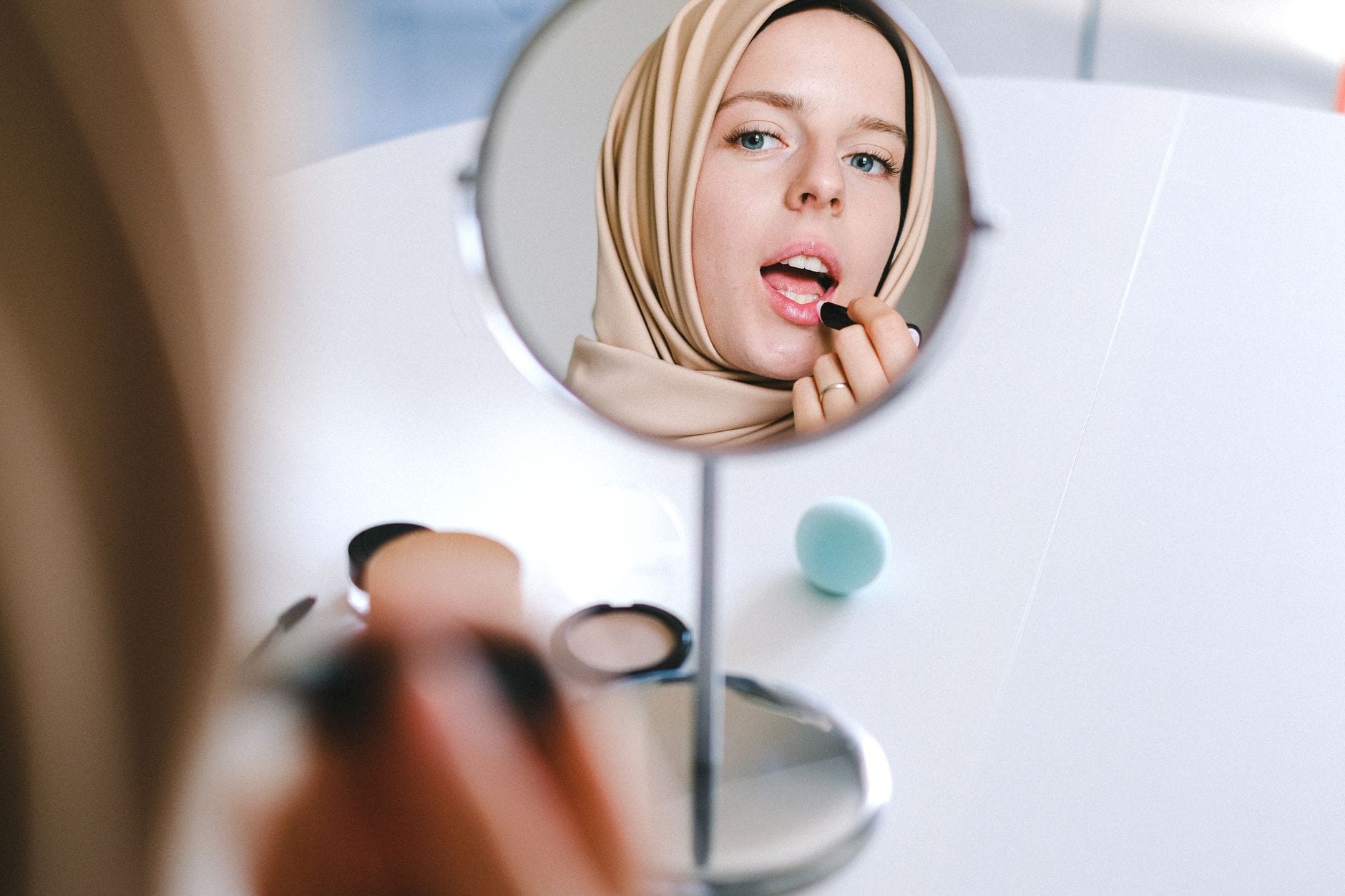 Muzułmanka w hijabie nakłada szminkę, oglądając się w lustrze