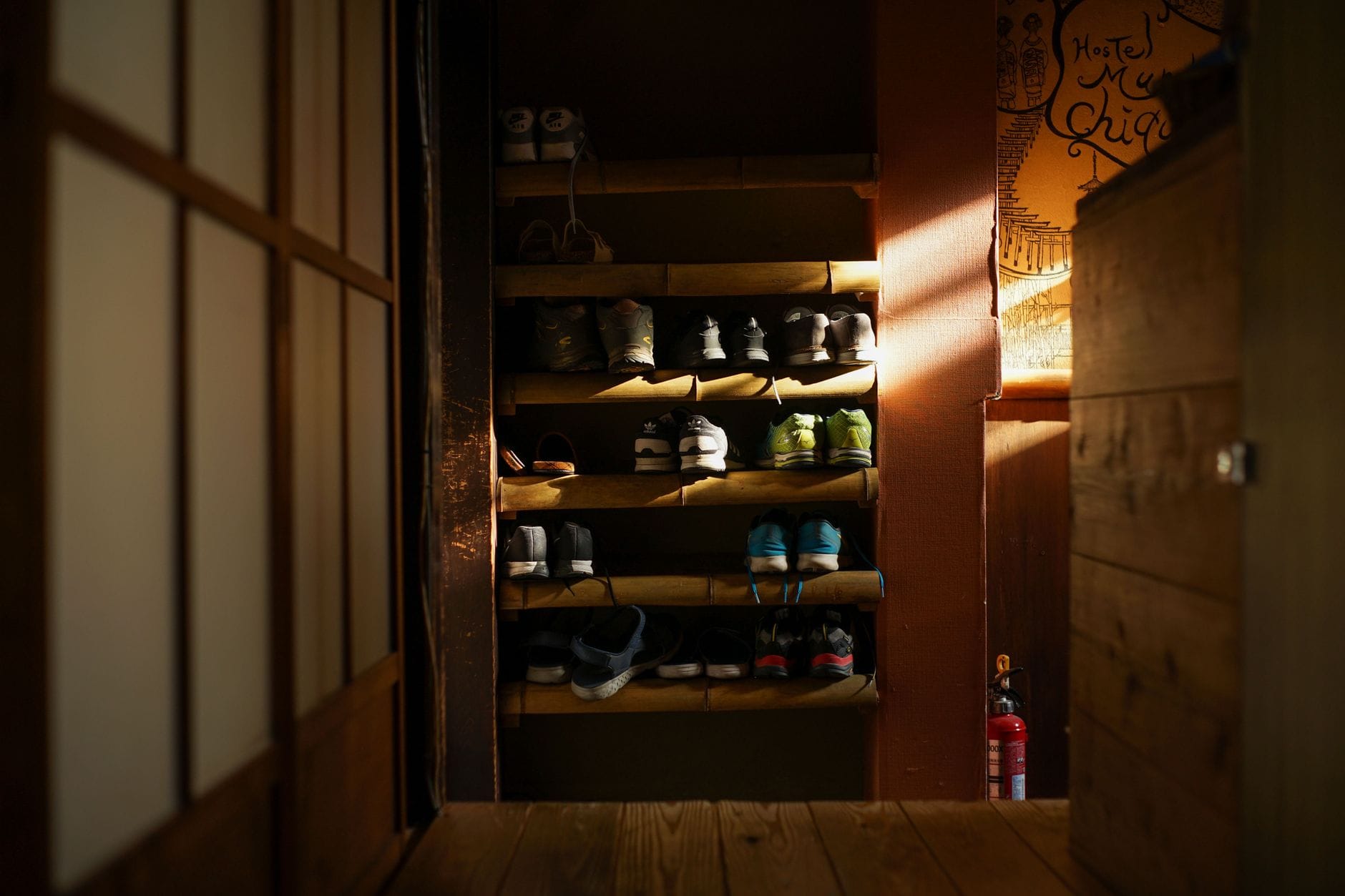 Drewniany regał na buty z równo ułożonymi sneakersami w przedpokoju
